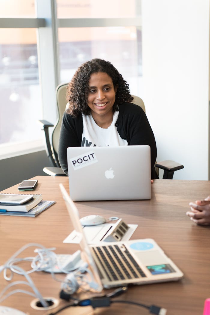 Cheerful woman using laptop in a modern workspace setting.